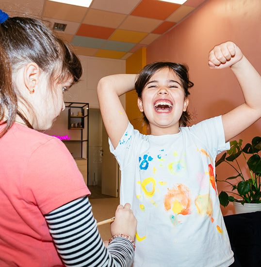 A young girl with dark hair laughing joyfully at school